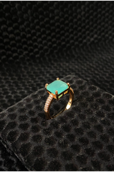 Gold ring with a turquoise gemstone on a black textured surface