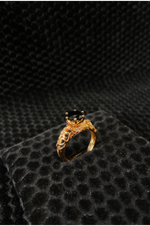 Gold ring with a black gemstone on a textured black surface