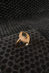 Gold ring with gray gemstones on a black textured surface