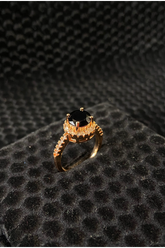 Gold ring with a black gemstone on a textured black surface