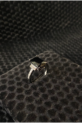 Silver ring with a black gemstone on a textured black surface