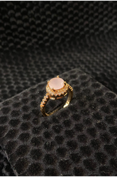 Gold ring with a pink gemstone on a black textured surface