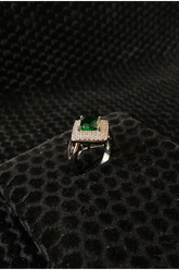 Silver ring with a green gemstone on a black textured surface