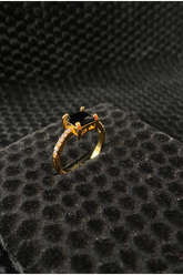 Gold ring with a black gemstone on a textured black surface