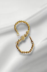 Gold bracelet with intricate design on a white fabric background