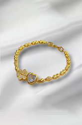 Gold bracelet with floral and heart designs on a white fabric background