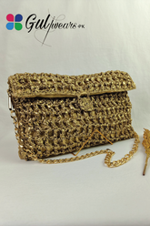 A cream gold crochet clutch bag with a chain strap, displayed against a white background.