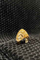 Gold ring with intricate design on a textured black surface