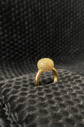 Gold ring with a textured design on a black textured surface