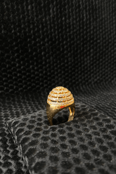 Gold ring with intricate design on a black textured surface
