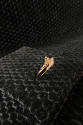 Gold ring with a black stone on a black textured surface