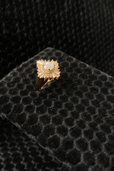 Gold ring with a white diamond gemstone on a black textured surface