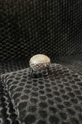 Silver ring with gemstones on a textured black surface
