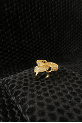 Gold ring with intricate design on a black textured surface