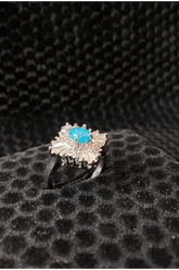 Silver ring with a blue gemstone on a black textured surface