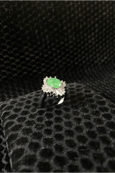 Ring with a green gemstone on a black textured surface