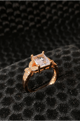 Rose gold ring with a large diamond on a black textured background