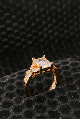 Rose gold ring with a diamond on a black textured background