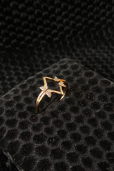 Gold ring with star design on a black textured surface