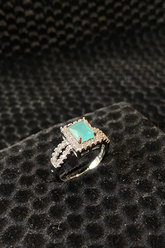 Silver ring with a green gemstone on a black textured surface