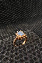 Gold ring with a blue gemstone on a textured black surface