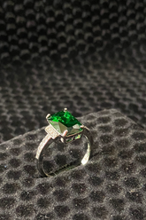 Ring with a green gemstone on a textured black surface