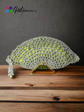 A silver clutch with Gota work and a half-moon design, displayed on a wooden surface.