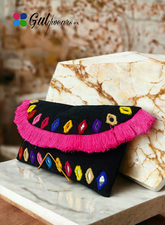 A black clutch bag with multicolored mirror work, displayed on a marble surface.