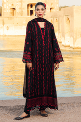Woman wearing a black and red traditional outfit standing in front of a water pool and architectural background.