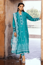 Woman wearing a teal embroidered dress standing outdoors.