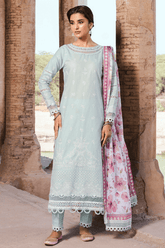 Woman in a light blue embroidered outfit with a pink floral dupatta standing in front of stone pillars.