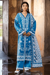 Woman wearing a blue embroidered traditional outfit standing in front of stone pillars.