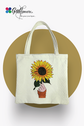 White painted tote bag with a sunflower design and a handle, displayed on a golden background.