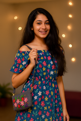 Woman wearing a floral dress holding a matching handbag with string lights in the background