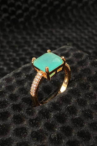 Gold ring with a turquoise gemstone on a black textured surface
