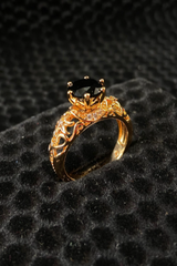 Gold ring with a black gemstone on a textured black surface