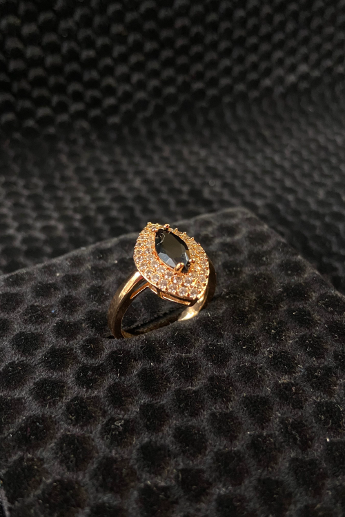 Gold ring with gray gemstones on a black textured surface