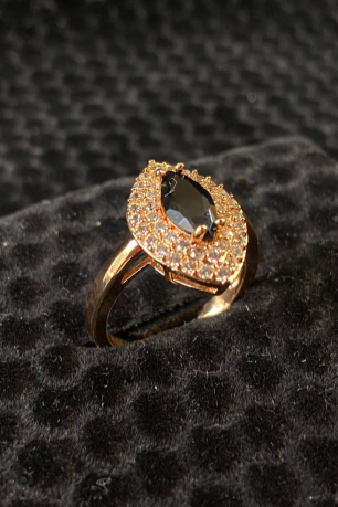 Gold ring with gray gemstones on a black textured surface