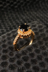 Gold ring with a black gemstone on a textured black surface