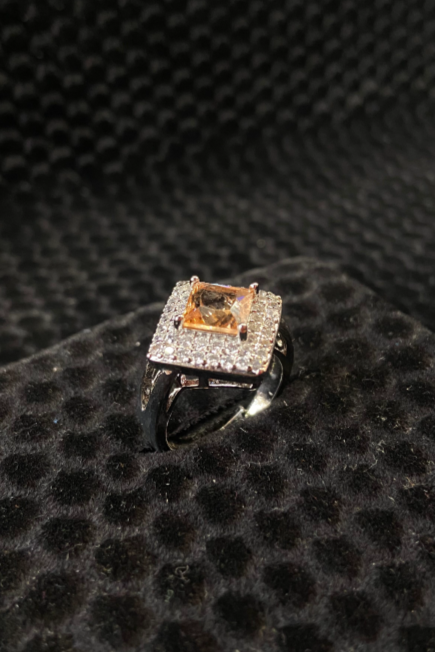 Ring with a central diamond and smaller stones on a black textured surface
