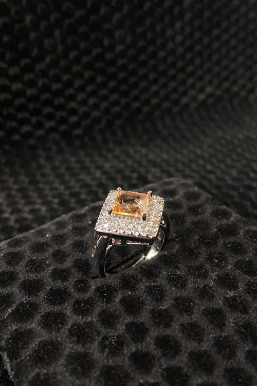 Ring with a central diamond and smaller stones on a black textured surface