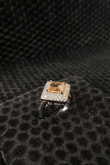 Ring with a central diamond and smaller stones on a black textured surface