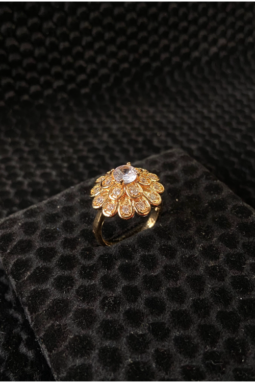 Gold ring with gemstones on a black textured surface