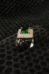 Silver ring with a green gemstone on a black textured surface