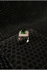 Silver ring with a green gemstone on a black textured surface