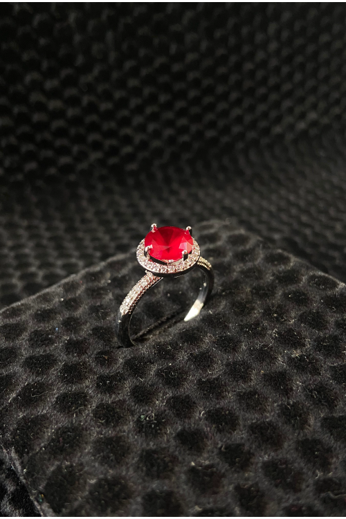 Ring with a red gemstone on a textured black surface