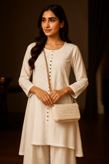 Woman in a white traditional outfit holding a beaded handbag against a dark background