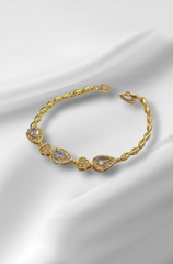 Gold bracelet with clear stones on a white satin background