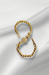 Gold bracelet with intricate design on a white fabric background