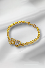 Gold bracelet with floral and heart designs on a white fabric background